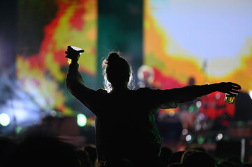 Silhouette of a woman with raised hands on a concert