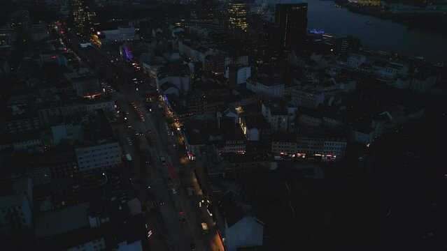 High angle view of colourful entertaining Reeperbahn boulevard. Tilt up reveal of evening cityscape. Hamburg, Germany