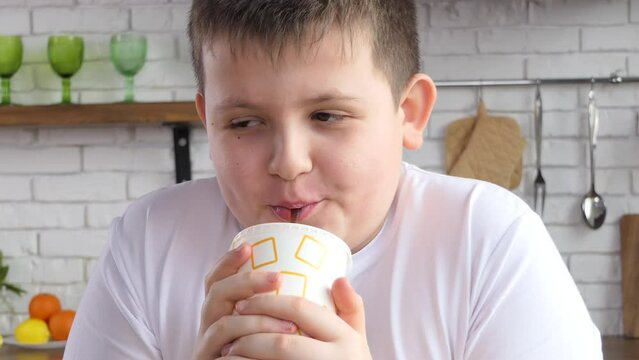 Close-up of a guy drinking from a paper cup through a straw. The guy drinks soda while sitting in a cafe. Cold coca cola with ice.