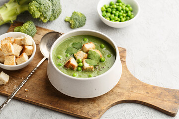 Green vegetable cream soup with pea, broccoli and croutons in ceramic bowl. Side view, close up