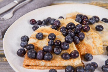 Portion of crepes with blueberry fruit on a wooden background
