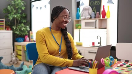 African woman preschool teacher using laptop at kindergarten - Powered by Adobe