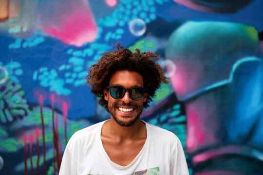 portrait young mixed race afro brazilian male smiling with glasses looking at camera