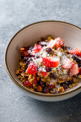 Granola with fresh berries on bowl on grey table vertical macro close up