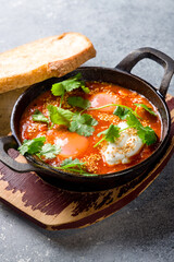 shakshuka classical on black cast iron on grey table vertical close up
