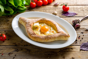 ajara Khachapuri with cheese, egg and butter, georgian kitchen on wooden table side view