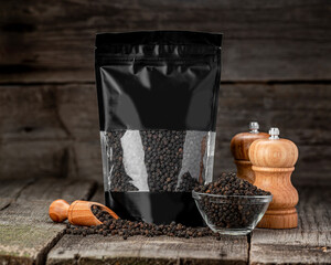 Black peppercorns in a package, on a wooden background