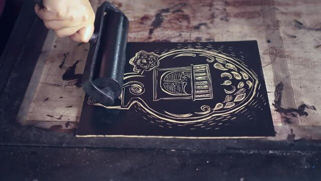 Crop unrecognizable woman lino printing in traditional technique workshop creating artwork with brayer