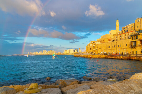 A rainbow appears above the skyline of Tel Aviv, seen from the old town harbor of the historic ancient city of Jaffa, Israel at sunset.	