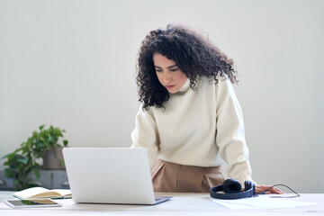 Young business woman company employee worker standing at desk working online on laptop. Female...