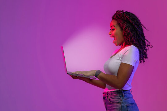 Surprised African American Woman Looking At Glowing Laptop Screen, Side View