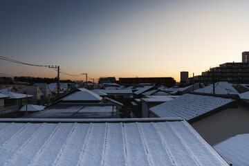 東久留米市の雪の朝、屋根に積もった雪と日の出前の空