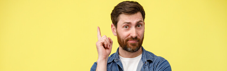 Obraz premium Smiling man raised finger up as sign he has new idea on yellow studio background