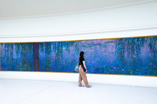 France, Paris - September 19, 2022: Visitors admire the giant waterlily Nympheas paintings by impressionist painter Claude Monet at the Musee de l Orangerie museum in Paris.