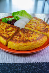 Spanish vegetarian food, portion of homemade tasty potato omelette tortilla de patatas with onion served in morning sunlights