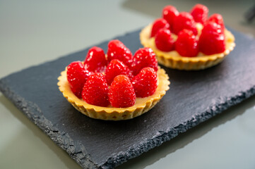 Artisanal baked small tart with cream and fresh ripe red raspberry