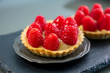Artisanal baked small tart with cream and fresh ripe red raspberry