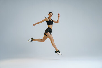 Fototapeta na wymiar Athletic active woman jumping on studio background. Dynamic movement
