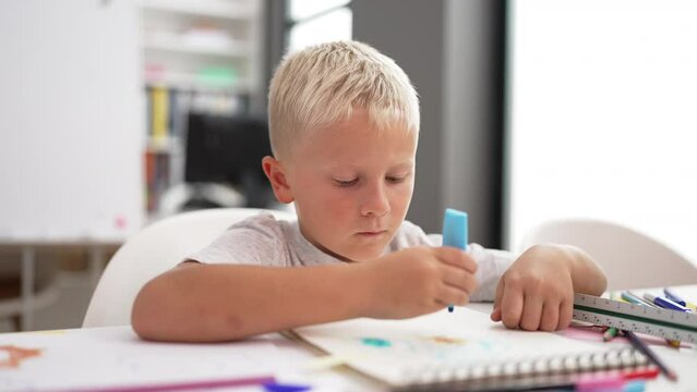 Adorable toddler student drawing on notebook doing ok gesture at classroom