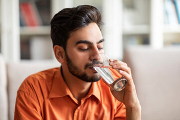 Healthy good-looking arab man drinking water at home