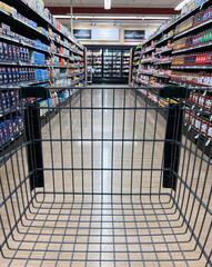 Looking down the aisle of a supermarket through a shopping cart.