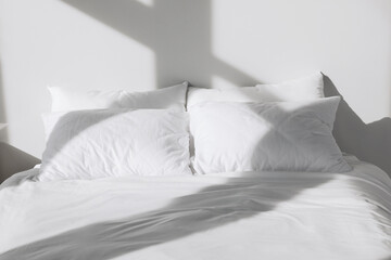 White soft pillows on bed in room