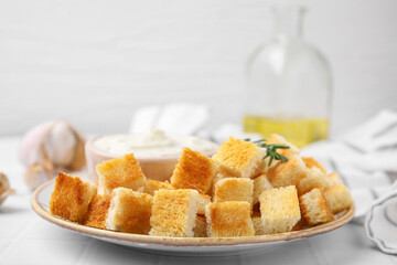 Delicious crispy croutons with rosemary on white table, closeup