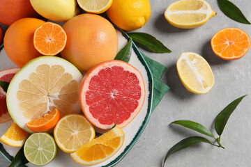 Fototapeta na wymiar Different citrus fruits with fresh leaves on light grey table, flat lay