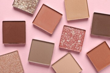 Different beautiful eye shadows on pink background, flat lay