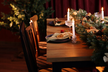 Dining table with burning candles and Christmas decor in stylish room. Interior design