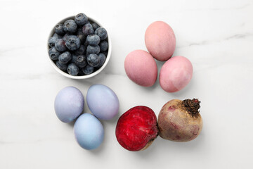 Colorful Easter eggs painted with natural dyes and ingredients on white marble table, flat lay