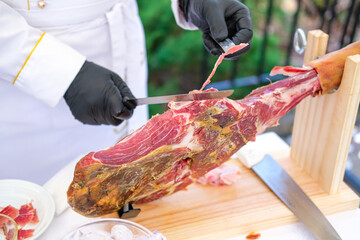 the chef cuts the prosciutto from the ham