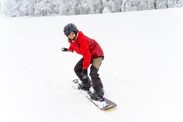 Young Asian woman practicing snowboard on snowy mountain slope at ski resort. Attractive girl enjoy...