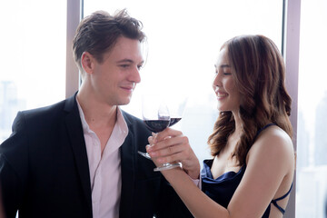Happy young couple holding with glass of wine cheer together in anniversary at restaurant for celebration, man and woman date with romantic and relationship, two people, valentine and holiday concept.