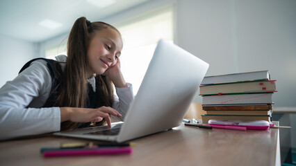 Caucasian girl studying on a laptop in a classroom. 