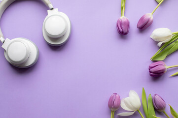 Wireless headphones and Spring tulips on violet background 