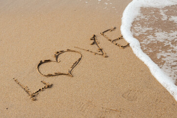 Love lettering on the sandy beach and sea water