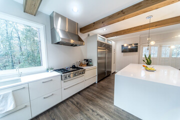 Fototapeta na wymiar A large luxury modern kitchen with white walls and wood beams and a large quartz quartzite island