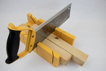 yellow hand saw and hard plastic miter box for hobby in home workshop