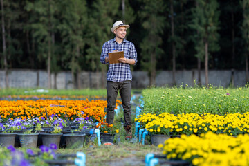 Portrait of Asian gardener holding clipboard while taking note on irrigation system on rural field farm for medicinal herb and cut flower usage