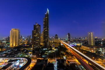 Fototapeta na wymiar Cityscape of Bangkok after sunset in blue hour with skyscraper and city view with road and traffic light.