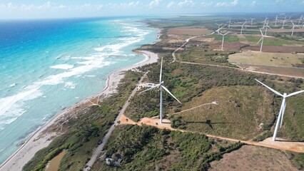 Wind farm shot next to caribbean beach from drone