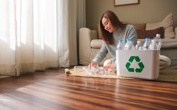 Portrait image of a woman collecting and separating recyclable garbage plastic bottles into a trash bin at home