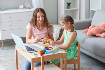 Little girl and her mother with toys having online psychologist session at home