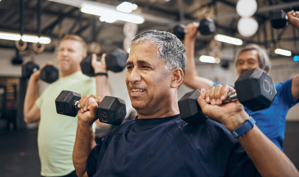 Training, group and senior men exercise together at the gym lifting weights with dumbbells equipment for strength. Elderly, old and fitness people workout in a sports club for wellness and health