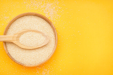 Wooden bowl of amaranth seeds on yellow background
