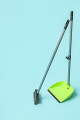 Broom with plastic dustpan on color background