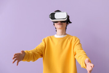 Teenage boy in VR glasses on lilac background