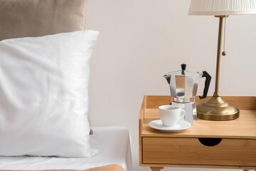 Fototapeta na wymiar Geyser coffee maker and cup of espresso on nightstand near bed