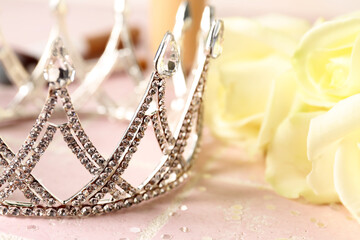 Beautiful tiara and roses on pink tile table, closeup. Prom concept